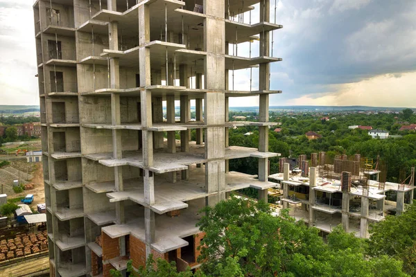 Aerial view of tower lifting crane and concrete frame of tall apartment residential building under construction in a city. Urban development and real estate growth concept. — Stock Image Aerial View Tower Lifting Crane Concrete Frame Tall Apartment Residential Royalty Free Stock Photos