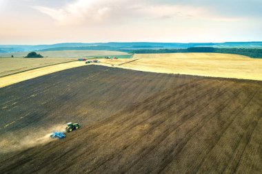 Sonbaharda hasattan sonra siyah tarım tarlasını süren bir traktörün hava görüntüsü.