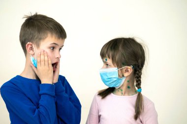 Mavi koruyucu maske takan kız ve erkek çocuk suçiçeği, kızamık ya da kızamık virüsü taşıyorlar. Koronovirüs salgını sırasında çocukların korunması. Covid-19 bulaşıcı hastalık konsepti.