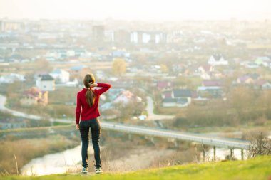 Genç bir kadın şehir manzarasının tadını çıkarıyor. Rahatlama, özgürlük ve sağIık kavramı.