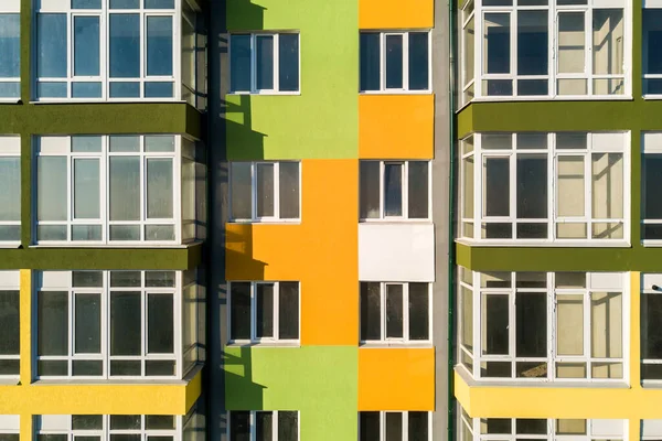 Birçok pencere ve balkonu olan yüksek bir apartman dairesinin havadan görünüşü.