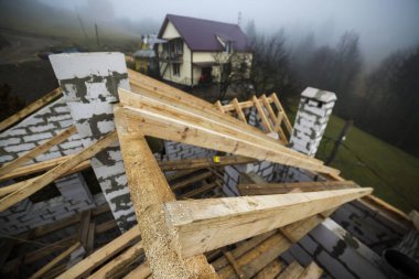 Ahşap kirişler ve boş köpük yalıtım bloklarından yapılmış kalasların çatı çerçevesinin üst görüntüsü. İnşaat, çatı, inşaat ve yenileme konsepti.