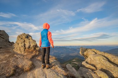 Genç çocuk yürüyüşçü dağlarda duruyor ve muhteşem dağ manzarasının tadını çıkarıyor..