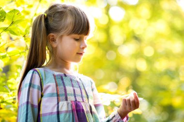 Sonbahar ormanında eğlenen mutlu kız çocuğunun portresi. Pozitif kadın çocuk, sonbahar parkında sıcak bir günün tadını çıkarıyor..