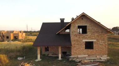 İnşaat halindeki metal kiremitlerle kaplı ahşap çatı yapısı olan bitmemiş evin havadan görüntüsü..