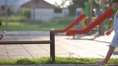 Anaokulunun bahçesinde yaz çocuk parkında annesinin bankta oturmasını bekleyen tatlı bir kız çocuğu..