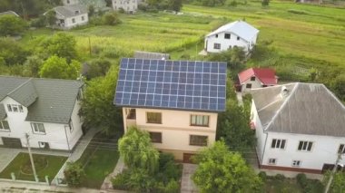 Çatıda mavi parlak güneş enerjili voltaik panelleri olan yeni, modern ev kulübesinin havadan görünüşü. Yenilenebilir ekolojik yeşil enerji üretim kavramı.