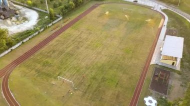 Yeşil çimenler ve su püskürten fıskiyelerle kaplı futbol sahası yüzeyinin yukarıdan görünüşü.