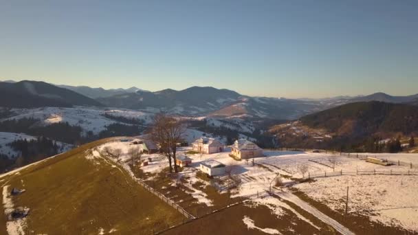 雪の上に散在する家と小さな村の空中ビューは ウクライナの冬と裸の暗いカルパチア山脈の丘をカバー — ストック動画