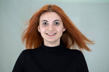 Uzun dalgalı saçları rüzgarda uçuşan güzel kızıl saçlı kızın yakın portresi..