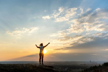 Yürüyüş yapan bir kadının silueti. Tek başına ayakta duruyor. Gün batımının tadını çıkarıyor. Kırsal alanda akşam vakti yaşayan kadın turist. Turizm, seyahat ve sağlıklı yaşam tarzı konsepti.