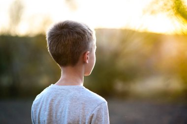 Yazın güneşli bir günde dışarıda duran çocuk dışarıda sıcak havanın tadını çıkarıyor. Dinlenme ve sağIık kavramı.