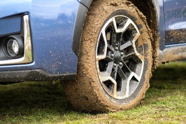 Lastik lastikli, sarı çamurla kaplı kirli araba tekerleğini kapat..