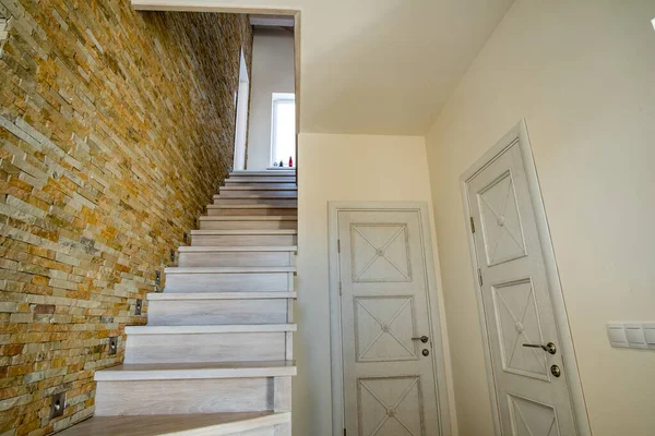 ロフトハウス内部のスタイリッシュな木製の現代的な階段 装飾的な石灰岩のレンガの壁と白いオークの階段を持つモダンな廊下 — ストック写真