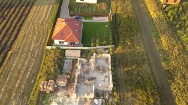 Biri ahşap çatı iskeleti ve diğeri de kırmızı kiremit çatılı iki özel evin yukarıdan aşağıya bakan görüntüsü..