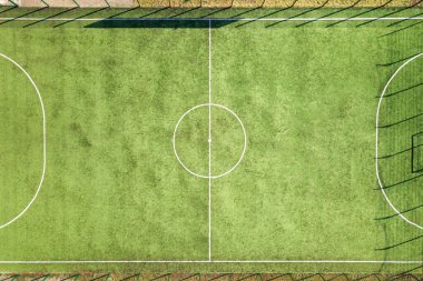 Yeşil futbol sahasının havadan görünüşü ve futbol oynayan oyuncular. İnsansız hava aracı, spor faaliyetleri sırasında çimen kaplı stadyumda tanınmayan küçük sporcuların resmini çekti..