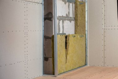 Alçıpan levhaları için hazırlanmış mineral kaya yünü yalıtımı ve metal iskeleti olan yenilenmiş bir odanın duvarı..