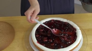 Kadın ellerine yakın, beyaz kremalı ve bisküvili vişneli pasta yapıyor..