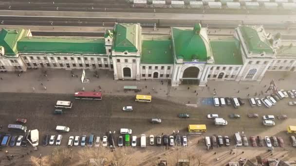 多くの車やバスの空中映像は ウクライナのイヴァーノ フランキーフスク市の鉄道駅ビルの前の忙しい街の通りに移動します — ストック動画