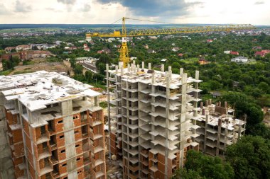 Kule görüntüsü, vinç kaldırma ve inşaat halindeki uzun apartmanların beton iskeleti. Kentsel kalkınma ve gayrimenkul büyüme kavramı.