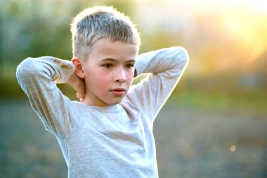 Yazın güneşli bir günde dışarıda duran çocuk dışarıda sıcak havanın tadını çıkarıyor. Dinlenme ve sağIık kavramı.