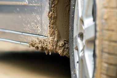 Lastik lastikli, sarı çamurla kaplı kirli araba tekerleğini kapat..