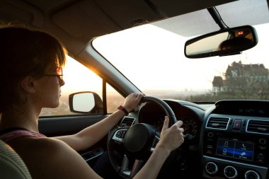 Güneş batarken direksiyon sallayan kadın sürücünün yakın görüntüsü..