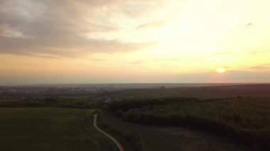 Baharda tarlaların üzerinde koyu sarı günbatımının havadan görünüşü.