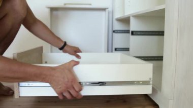 Erkek marangoz ellerinin mobilya dolabını monte etmesi ve yeni ahşap çekmece takması..