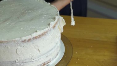 Kadın ellerine yakın beyaz krema ve bisküviyle tatlı pasta yapıyor..