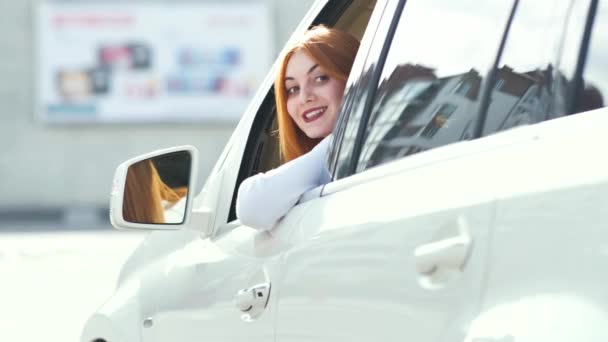 若い赤毛の女性ドライバーが後ろを振り返って車を運転する — ストック動画