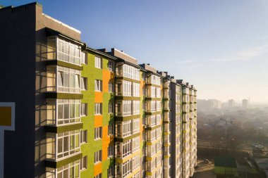 Birçok pencere ve balkonu olan yüksek bir apartman dairesinin havadan görünüşü.