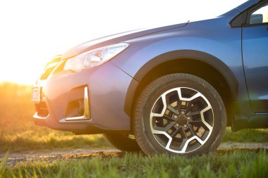 Yeşil çimenlikteki mavi off-road vagonunu kapatın. Otomobille seyahat, vahşi yaşam macerası, keşif gezisi ya da bir SUV otomobili ile aşırı seyahat. Offroad 4x4 aracı gün doğumunda arazide olacak..