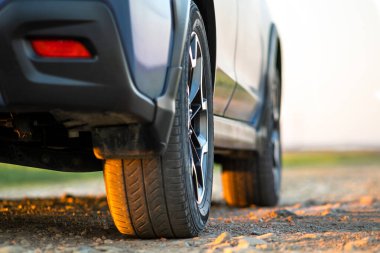 Çakıl yolundaki mavi off-road araba tekerleğini kapatın. Otomobille seyahat, vahşi yaşam macerası, keşif gezisi ya da bir SUV otomobili ile aşırı seyahat. Offroad 4x4 aracı gün doğumunda arazide olacak..
