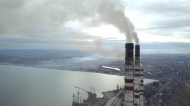 Kömür santralinden gelen gri dumanlı yüksek baca borularının havadan görüntüsü. Fosil yakıtla elektrik üretimi.