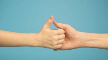 Mavi arka planda izole bir şekilde oynayan iki çocuğun elini kapat..