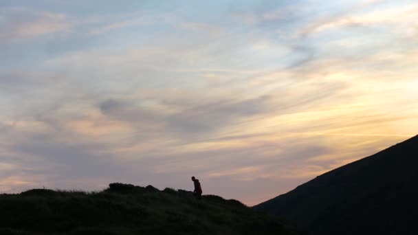 日落时登山者像获胜者一样爬上山顶的黑暗轮廓 — 图库视频影像