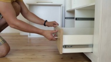 Erkek marangoz ellerinin mobilya dolabını monte etmesi ve yeni ahşap çekmece takması..