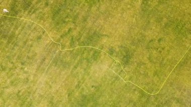 Yeşil çimenler ve su püskürten fıskiyelerle kaplı futbol sahası yüzeyinin yukarıdan görünüşü.