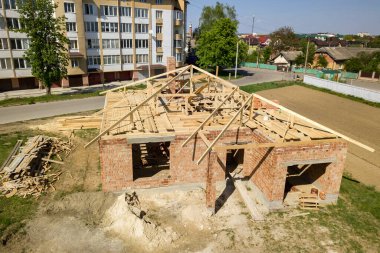 İnşaat halindeki ahşap çatı iskeleti olan bitmemiş tuğla evin havadan görüntüsü..