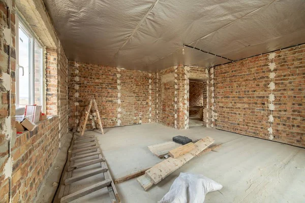 コンクリートの床と裸の壁と未完成のレンガ造りの家のインテリアは 建設中の漆喰の準備ができています 不動産開発 — ストック写真
