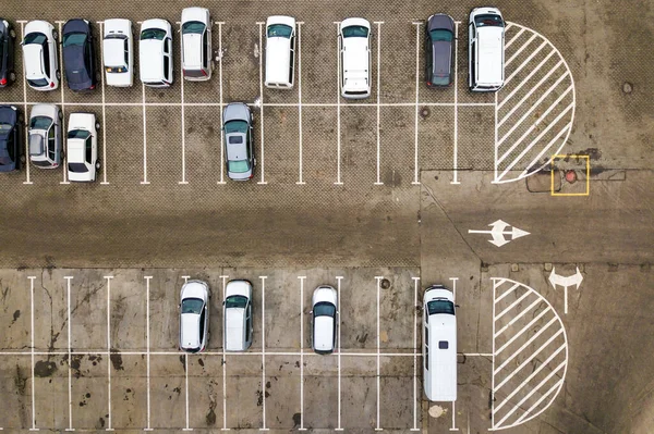 Top down aerial view of many cars on a parking lot of supermarket or on sale car dealer market.