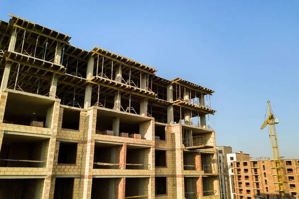 High multi storey residential apartment building under construction. Concrete and brick framing of high rise housing. Real estate development in urban area.