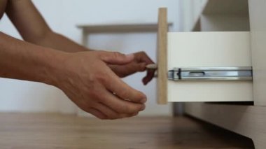 Erkek marangoz ellerinin mobilya dolabını monte etmesi ve yeni ahşap çekmece takması..