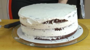 Kadın ellerine yakın beyaz krema ve bisküviyle tatlı pasta yapıyor..