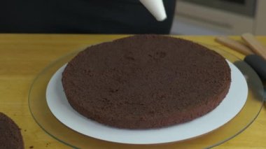 Kadın ellerine yakın beyaz krema ve bisküviyle tatlı pasta yapıyor..
