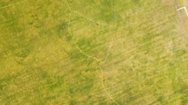 Yeşil çimenler ve su püskürten fıskiyelerle kaplı futbol sahası yüzeyinin yukarıdan görünüşü.