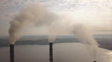 Kömür santralinden gelen gri dumanlı yüksek baca borularının havadan görüntüsü. Fosil yakıtla elektrik üretimi.