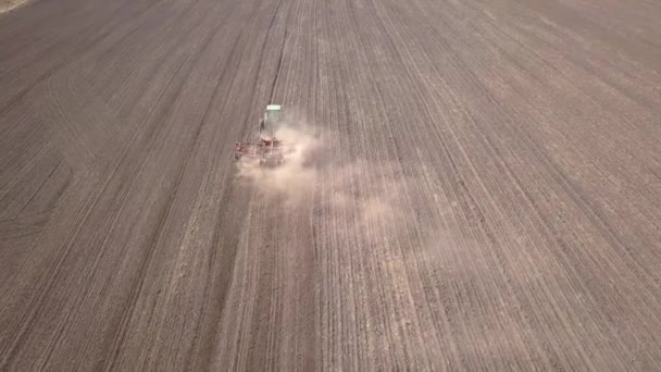 Vue aérienne de haut en bas du tracteur vert cultivant le sol et semant un champ sec. Exploitant agricole préparant des terres avec cultivateur de semis dans le cadre d'activités préalables à l'ensemencement au début du printemps.