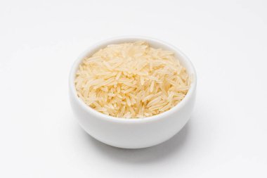 Beyaz arka planda Basmati pirinç kasesi. Pirinç ot tohumlarından gelir, en çok tüketilen temel besin maddesidir. Basmati pilavı, Hint mutfağında sıklıkla kullanılan aromatik uzun tahıllı pirinç türüdür..